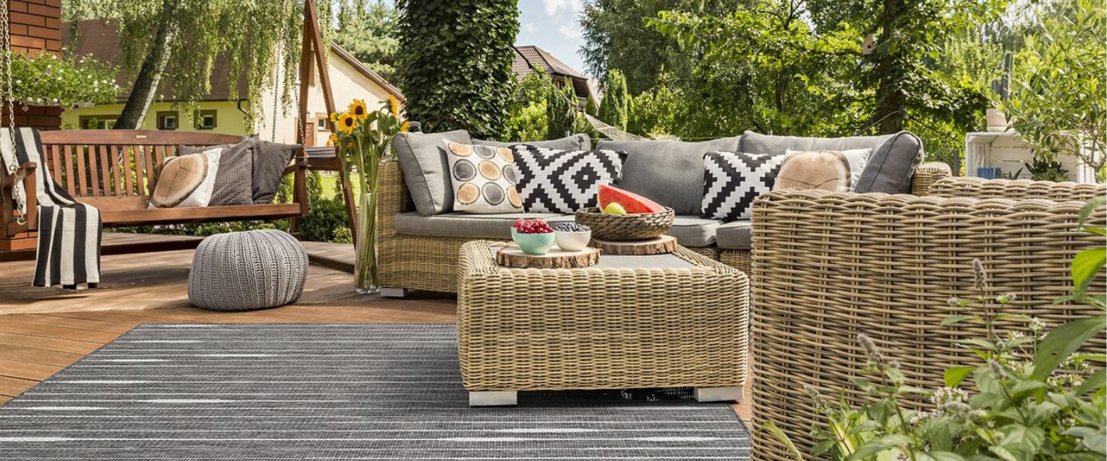 Terassin harmaa matto ja rottinkikalusteet