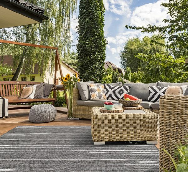 Terassin harmaa matto ja rottinkikalusteet